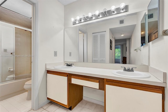 full bathroom with tile patterned flooring, vanity, combined bath / shower with glass door, and toilet