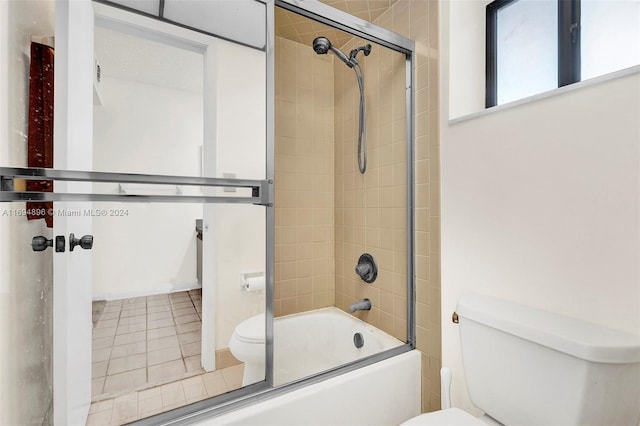 bathroom featuring shower / bath combination with glass door, tile patterned flooring, and toilet