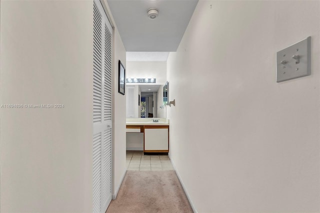 hall with light colored carpet and sink