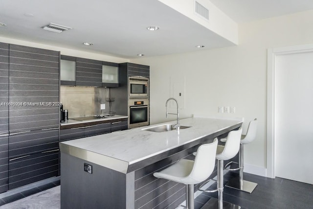 kitchen featuring a breakfast bar area, sink, appliances with stainless steel finishes, and an island with sink