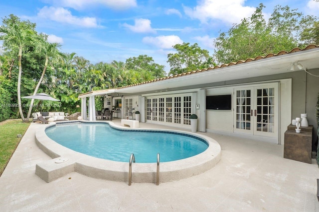 view of pool with outdoor lounge area, a patio, and french doors