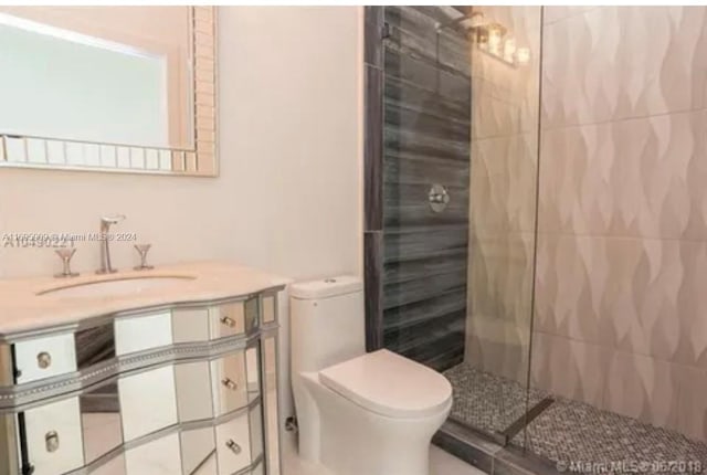 bathroom featuring vanity, toilet, and tiled shower