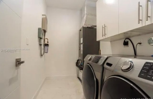 clothes washing area featuring separate washer and dryer and cabinets