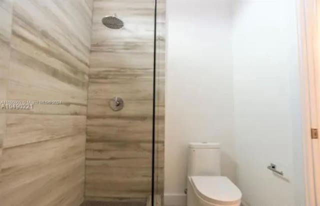 bathroom featuring a tile shower and toilet