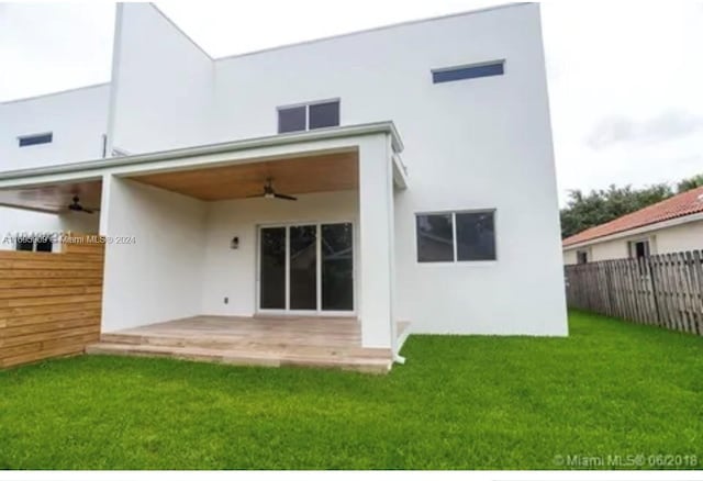 back of house featuring a lawn, ceiling fan, and a patio