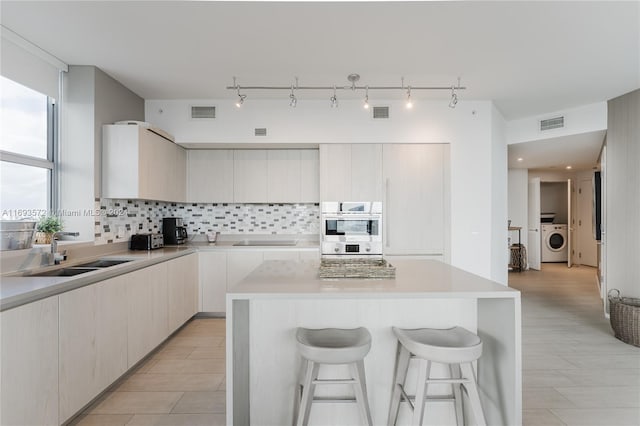 kitchen with backsplash, sink, a kitchen island, and washer / dryer