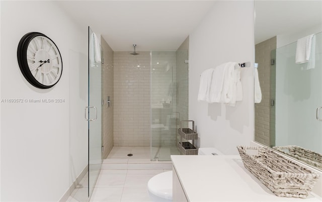 bathroom featuring toilet, vanity, tile patterned floors, and a shower with door