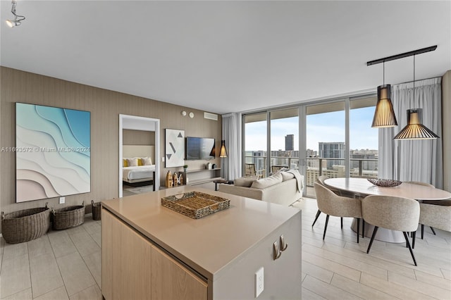 kitchen with decorative light fixtures, floor to ceiling windows, a kitchen island, and light hardwood / wood-style floors