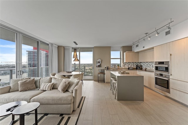 kitchen featuring plenty of natural light, a kitchen island, stainless steel double oven, and decorative light fixtures