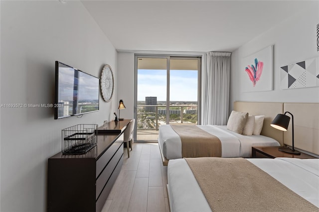 bedroom featuring access to outside, light hardwood / wood-style flooring, and expansive windows