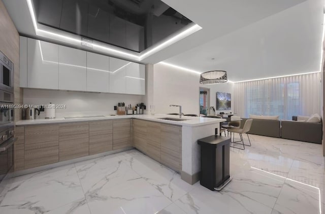 kitchen featuring white cabinetry, sink, kitchen peninsula, stovetop, and black oven