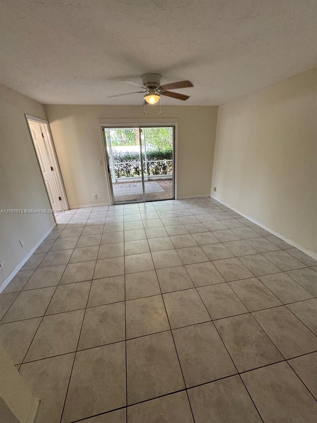 tiled empty room with ceiling fan and a textured ceiling