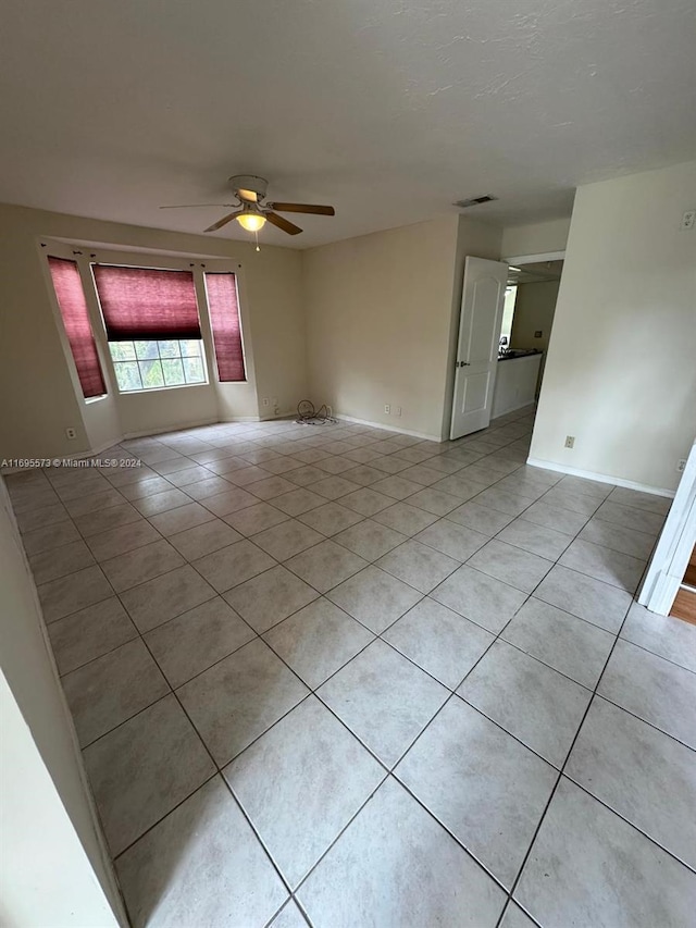 tiled spare room featuring ceiling fan