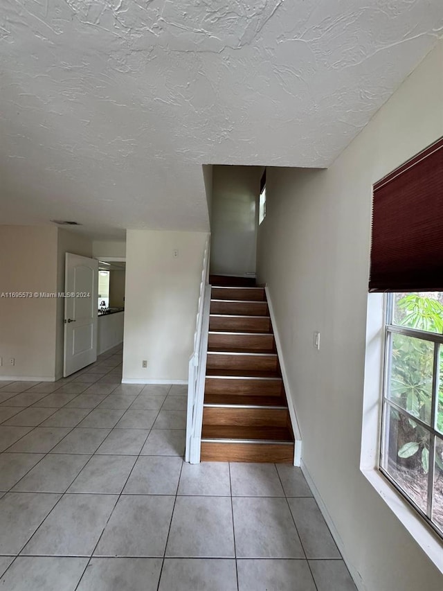 staircase with tile patterned floors and a textured ceiling