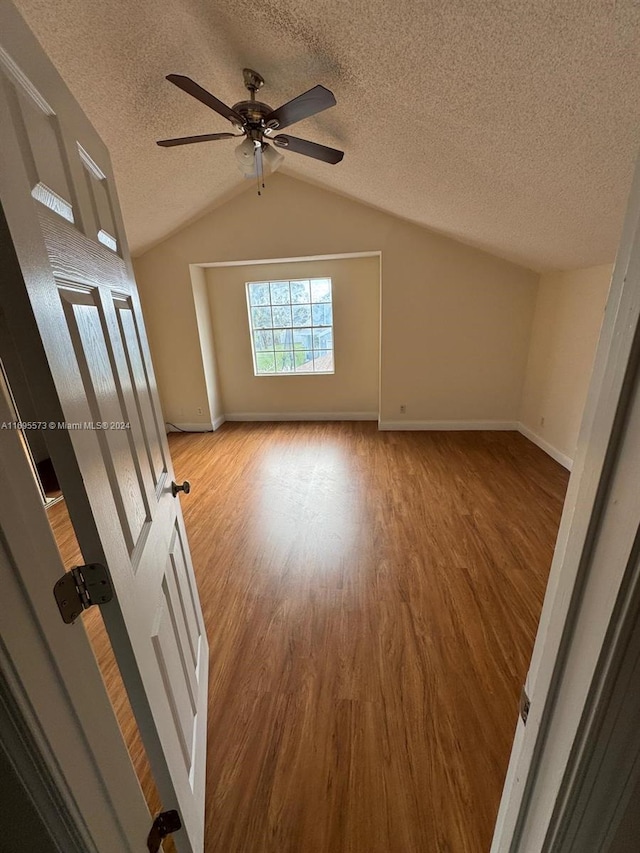 interior space featuring hardwood / wood-style flooring, ceiling fan, a textured ceiling, and vaulted ceiling