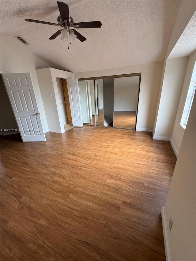 empty room with vaulted ceiling, ceiling fan, light hardwood / wood-style flooring, and a textured ceiling