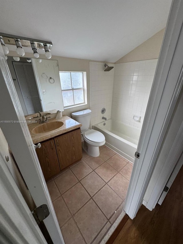 full bathroom with tile patterned floors, vanity, tiled shower / bath combo, toilet, and lofted ceiling