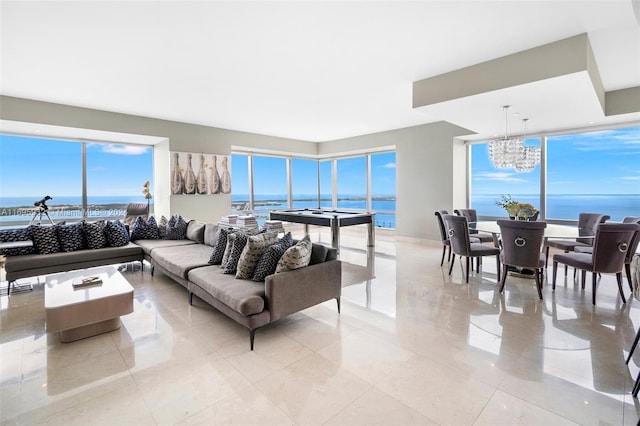 living room featuring a notable chandelier, a water view, light tile patterned floors, and a wealth of natural light