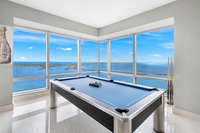 rec room with plenty of natural light, a water view, light tile patterned floors, and billiards