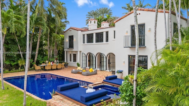 rear view of property featuring a patio and a pool with hot tub