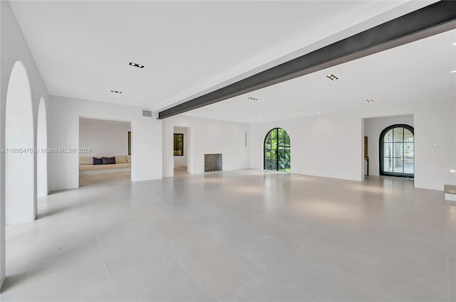 unfurnished room featuring beamed ceiling and light tile patterned floors