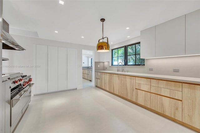 kitchen with light brown cabinets, hanging light fixtures, and sink