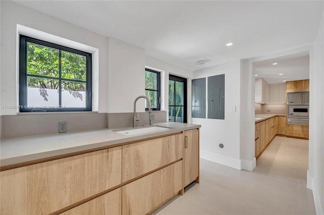 kitchen featuring light brown cabinets, electric panel, a wealth of natural light, and sink