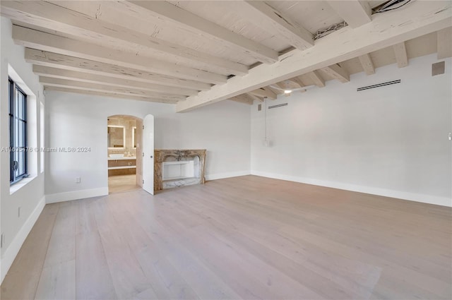 unfurnished living room with beamed ceiling and wood-type flooring