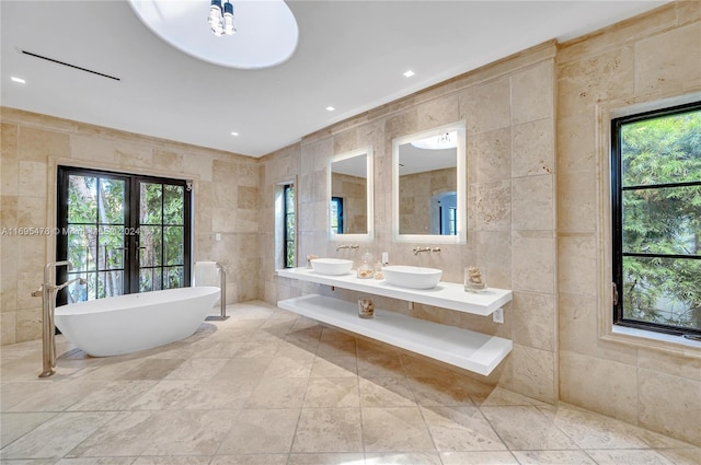 bathroom with a bathing tub, vanity, tile walls, and a wealth of natural light