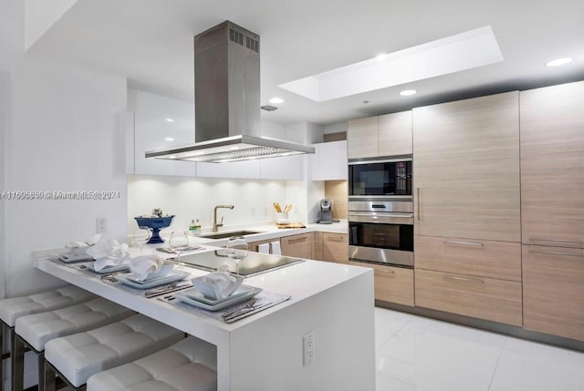 kitchen featuring island range hood, a kitchen bar, kitchen peninsula, and sink