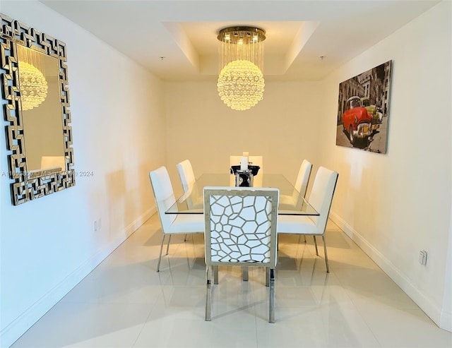 tiled dining space featuring a tray ceiling and a chandelier