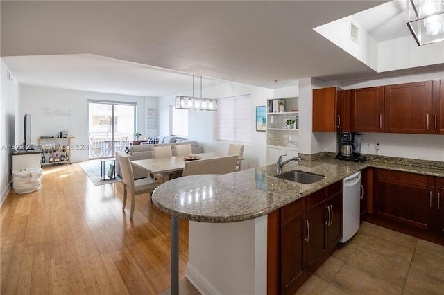 kitchen featuring white dishwasher, sink, stone countertops, light hardwood / wood-style floors, and kitchen peninsula