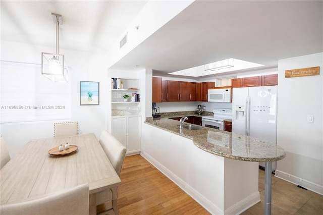 kitchen with kitchen peninsula, light stone countertops, white appliances, decorative light fixtures, and light hardwood / wood-style flooring