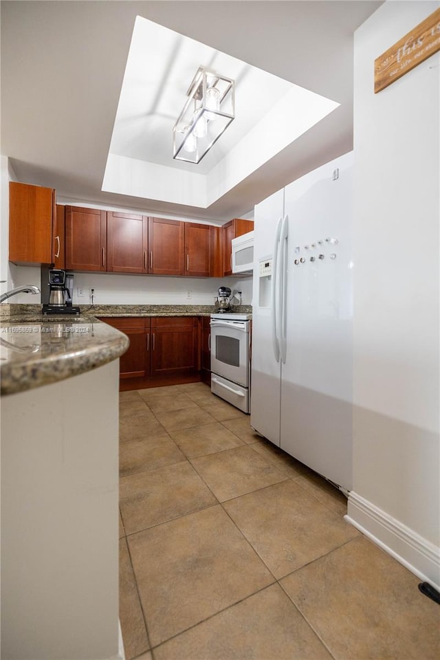 kitchen featuring a raised ceiling, sink, light tile patterned floors, and white appliances