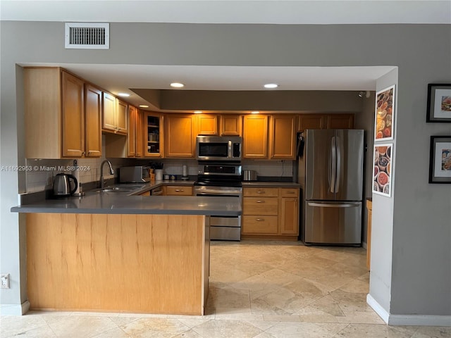 kitchen featuring kitchen peninsula, sink, appliances with stainless steel finishes, and tasteful backsplash