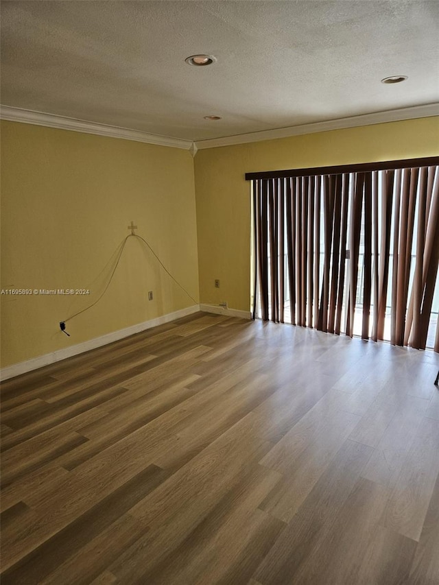 empty room with hardwood / wood-style floors, a textured ceiling, and crown molding