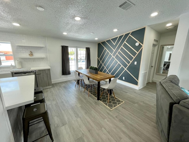 dining space featuring a textured ceiling and light hardwood / wood-style flooring