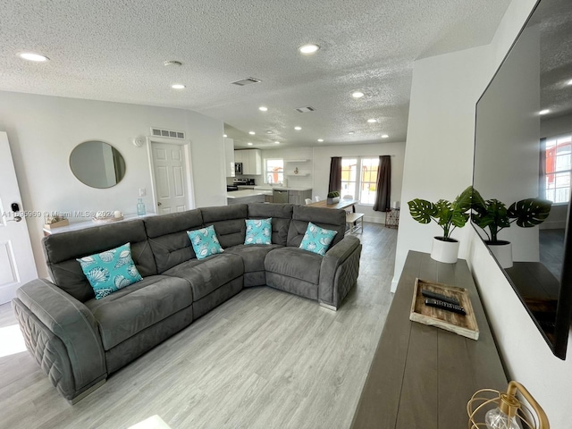 living room with a textured ceiling and light wood-type flooring