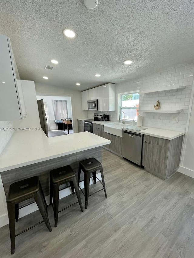 kitchen featuring stainless steel appliances, white cabinetry, and light hardwood / wood-style floors