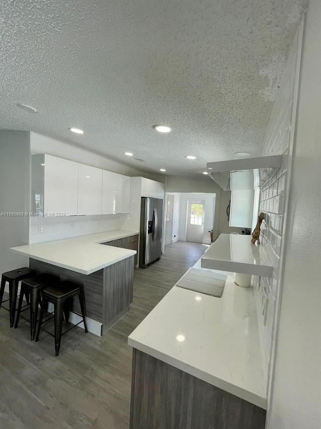 kitchen featuring white cabinets, stainless steel fridge with ice dispenser, a breakfast bar, and dark hardwood / wood-style floors