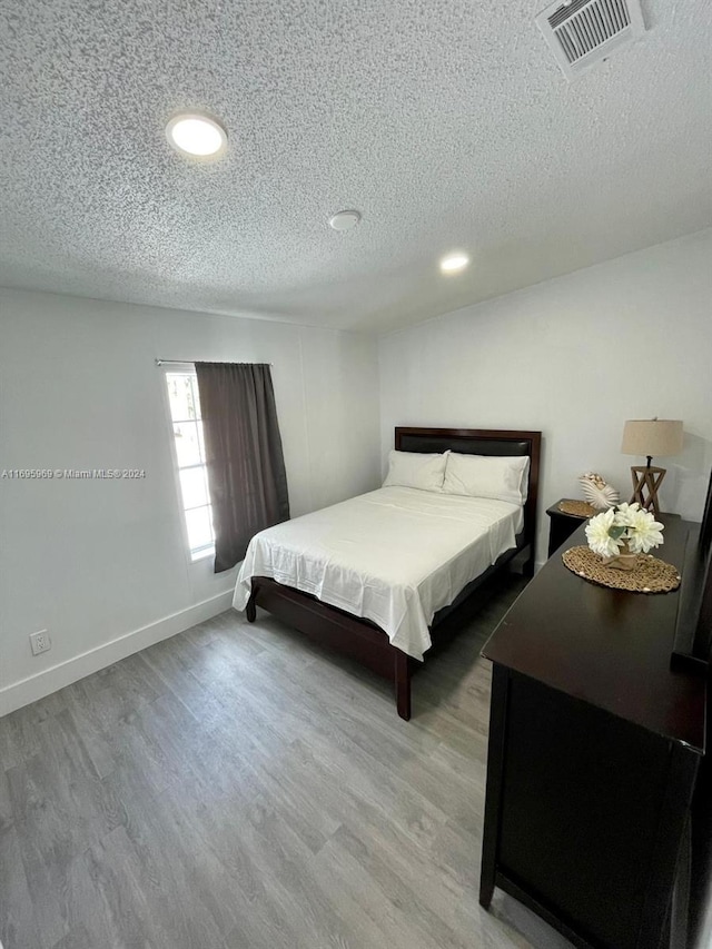 bedroom with a textured ceiling and hardwood / wood-style flooring