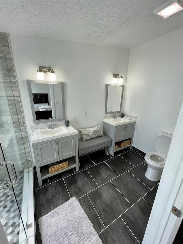 bathroom with tile patterned floors, vanity, an enclosed shower, and a textured ceiling