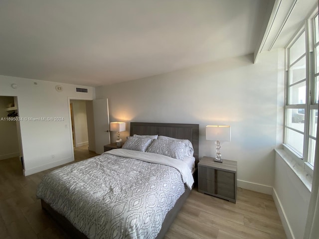 bedroom with multiple windows and light wood-type flooring