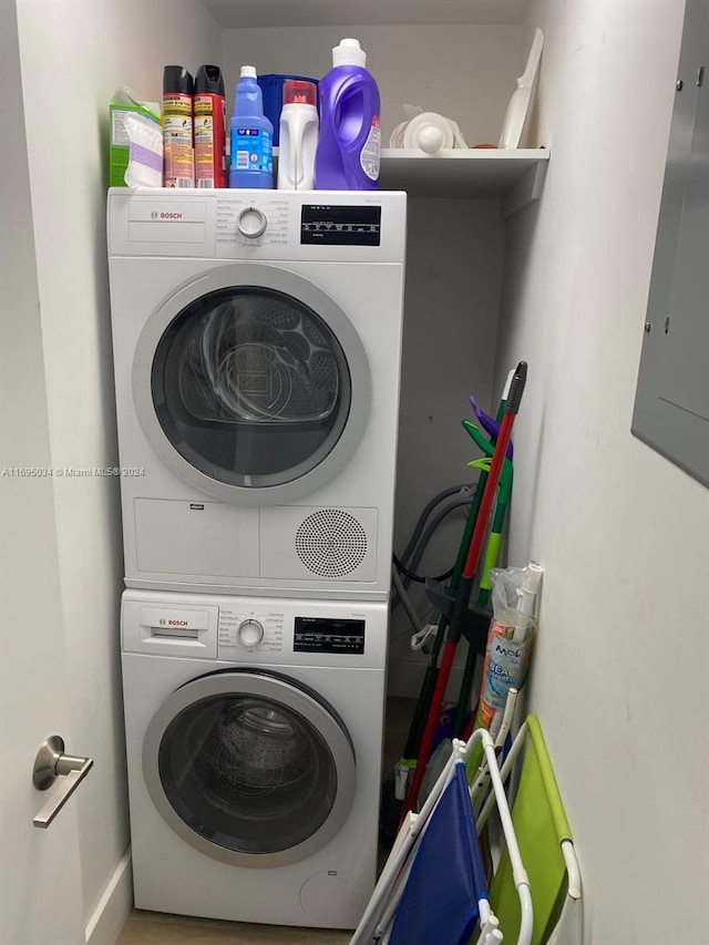 laundry room featuring electric panel and stacked washing maching and dryer