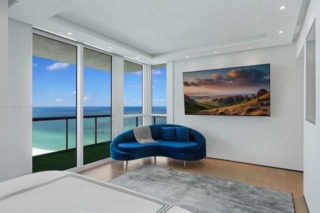 bedroom featuring hardwood / wood-style flooring, a raised ceiling, and a wall of windows