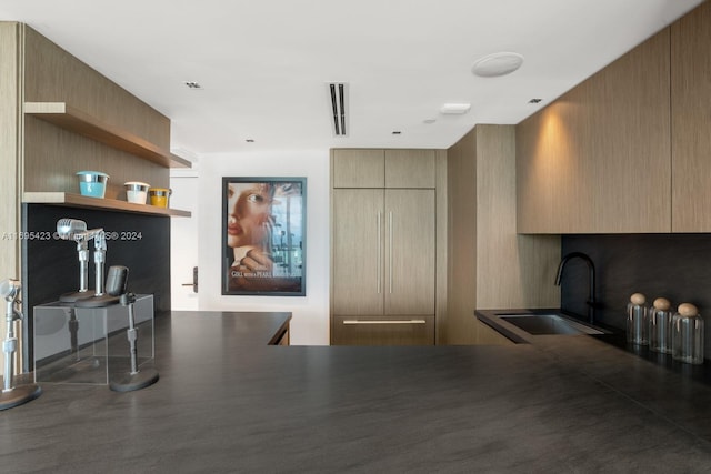 kitchen with kitchen peninsula, light brown cabinetry, and sink