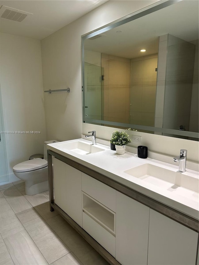 bathroom featuring tile patterned flooring, vanity, toilet, and a shower with shower door