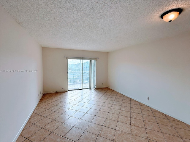 empty room with light tile patterned floors and a textured ceiling