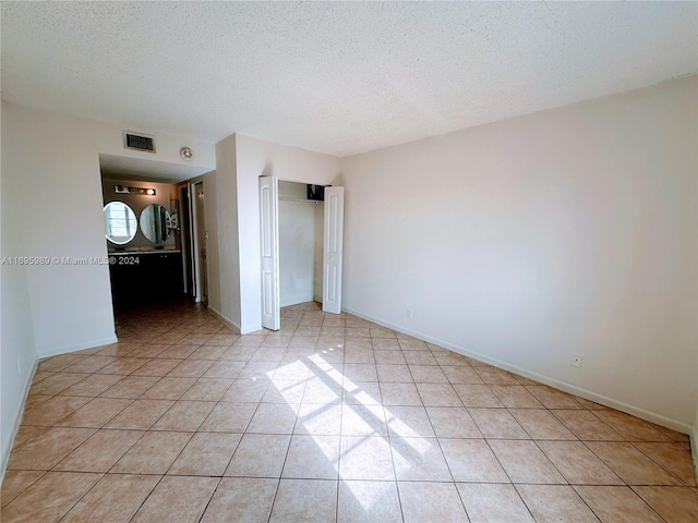 unfurnished bedroom with light tile patterned flooring and a textured ceiling