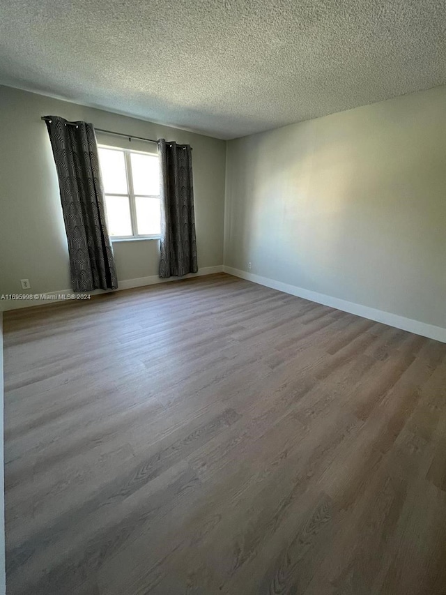 unfurnished room featuring hardwood / wood-style floors and a textured ceiling